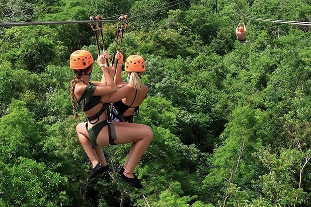 Visitante deslizándose en tirolesa sobre la selva en Xplor